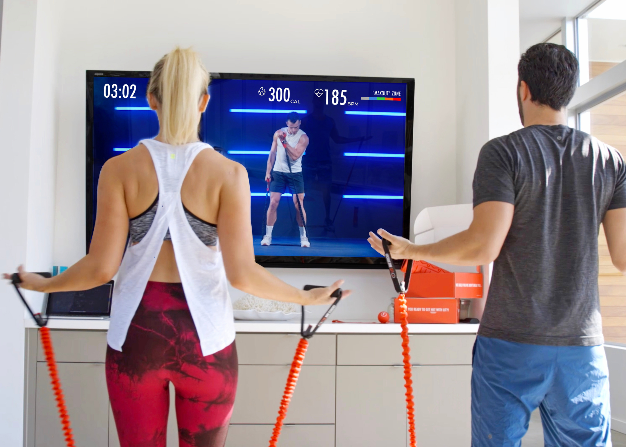 A man and woman watching LIT On-Demand and doing workout with LIT Axis resistance band