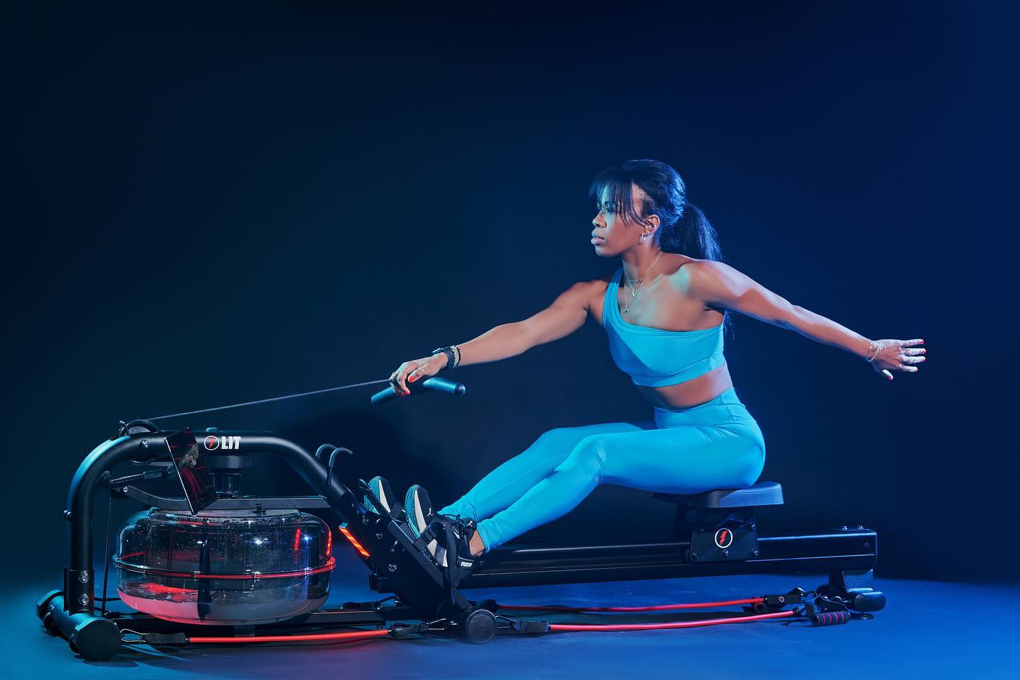 Woman in blue outfit, working out on the LIT Strength machine one handed