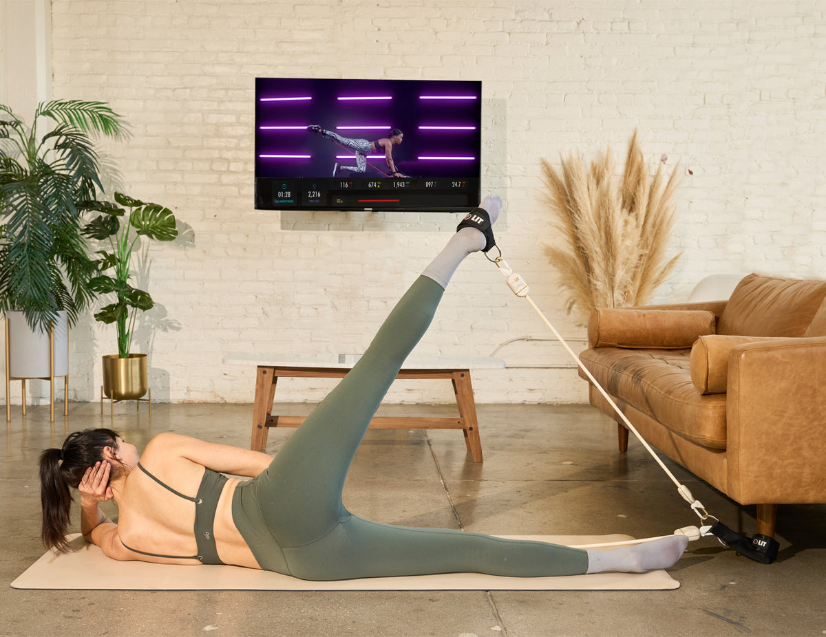 Woman using LIT Axis smart resistance band for Pilates workout