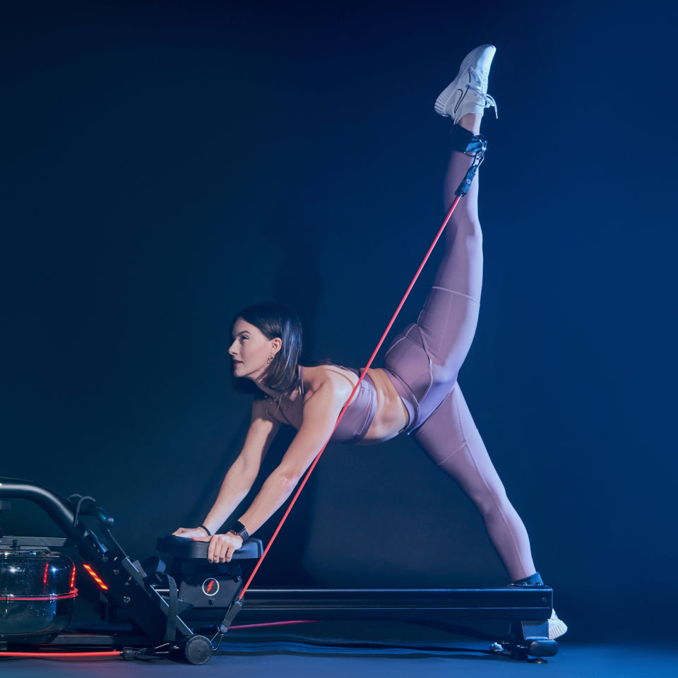 Woman in purple leggings, doing pilates on the Lit Strength Machine