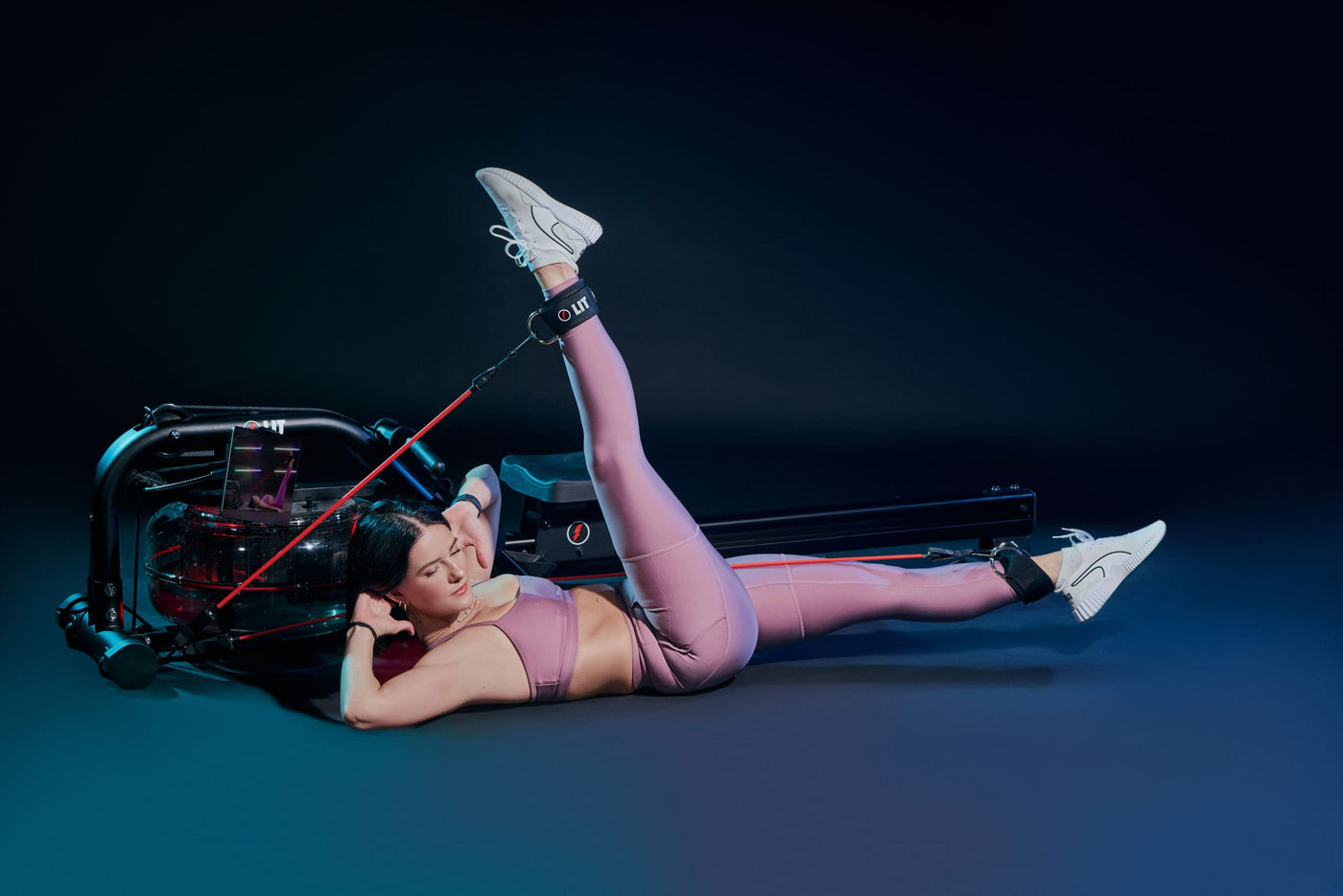 Woman in purple outfit doing leg lifts on the LIT Strength machine