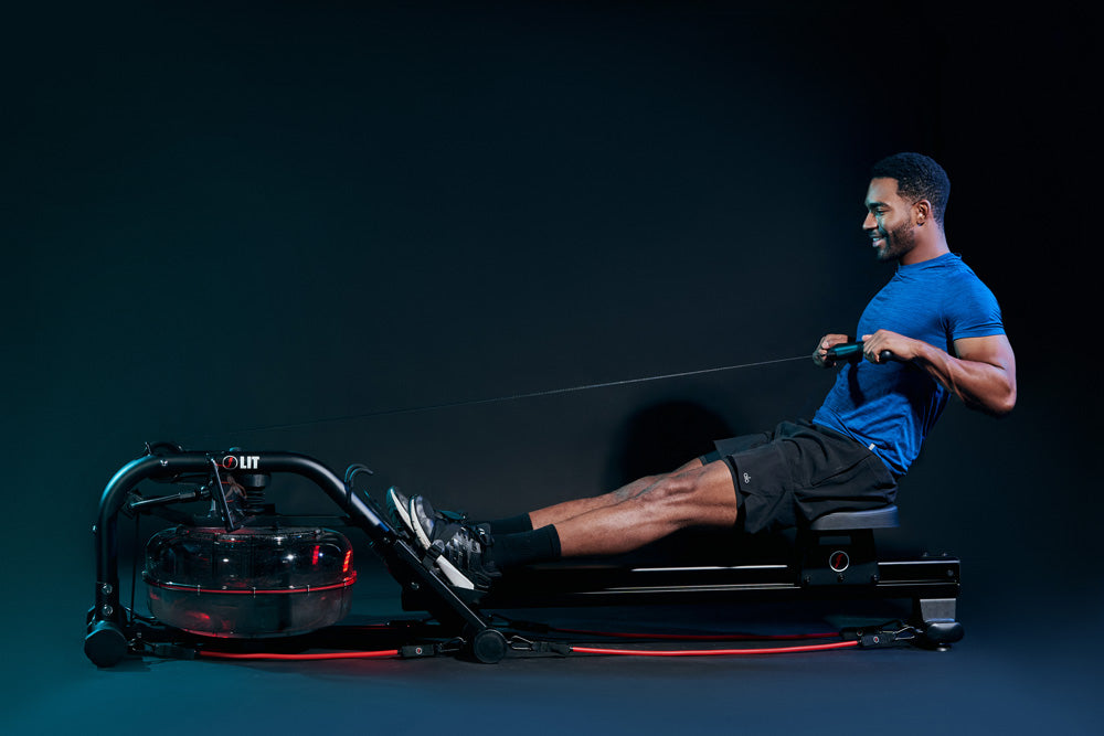 Male in blue shirt rowing on the LIT Strength machine in a dark studio