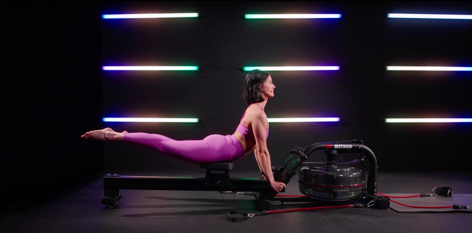 female in purple doing pilates on the lit machine